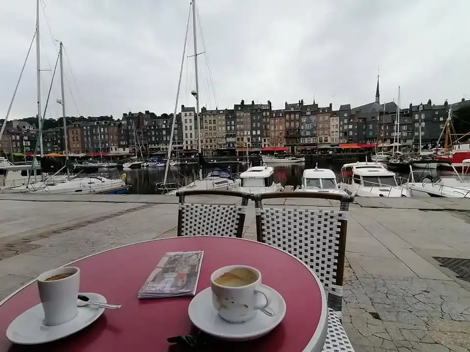 Deux tasses de café sur une table rose devant le port de Honfleur
