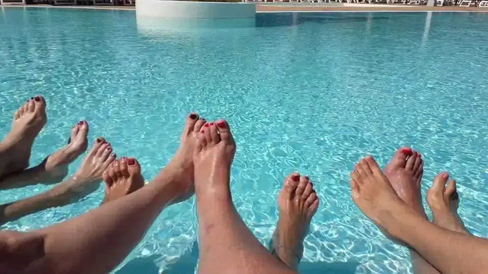 Des pieds tendus au-dessus de l’eau turquoise d’une piscine