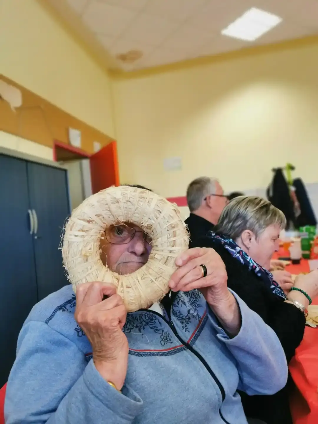Une participante passe un anneau de paille devant son visage en riant