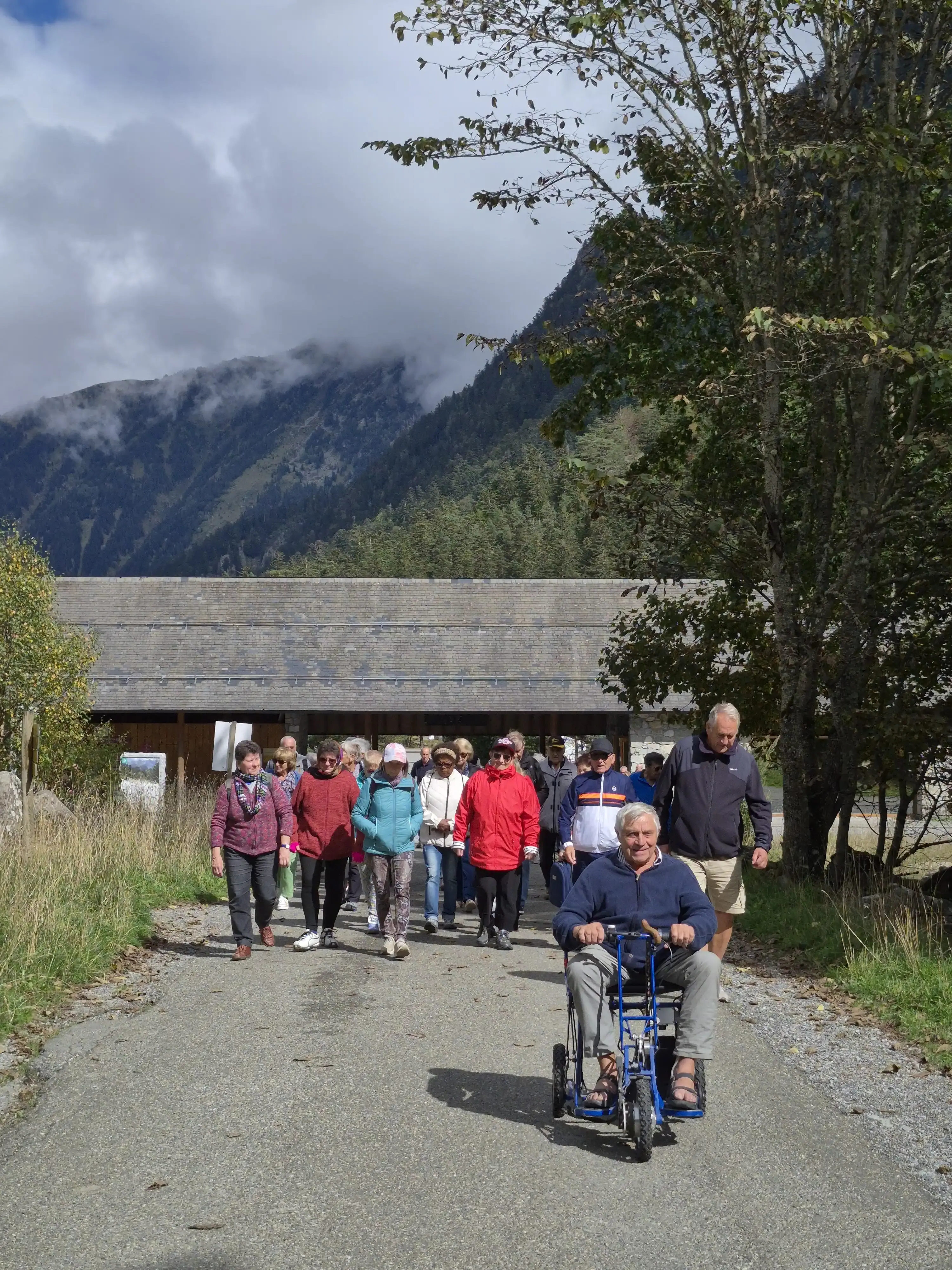 Un groupe de promeneurs sur un chemin de montagne, dont une personne en fauteuil roulant