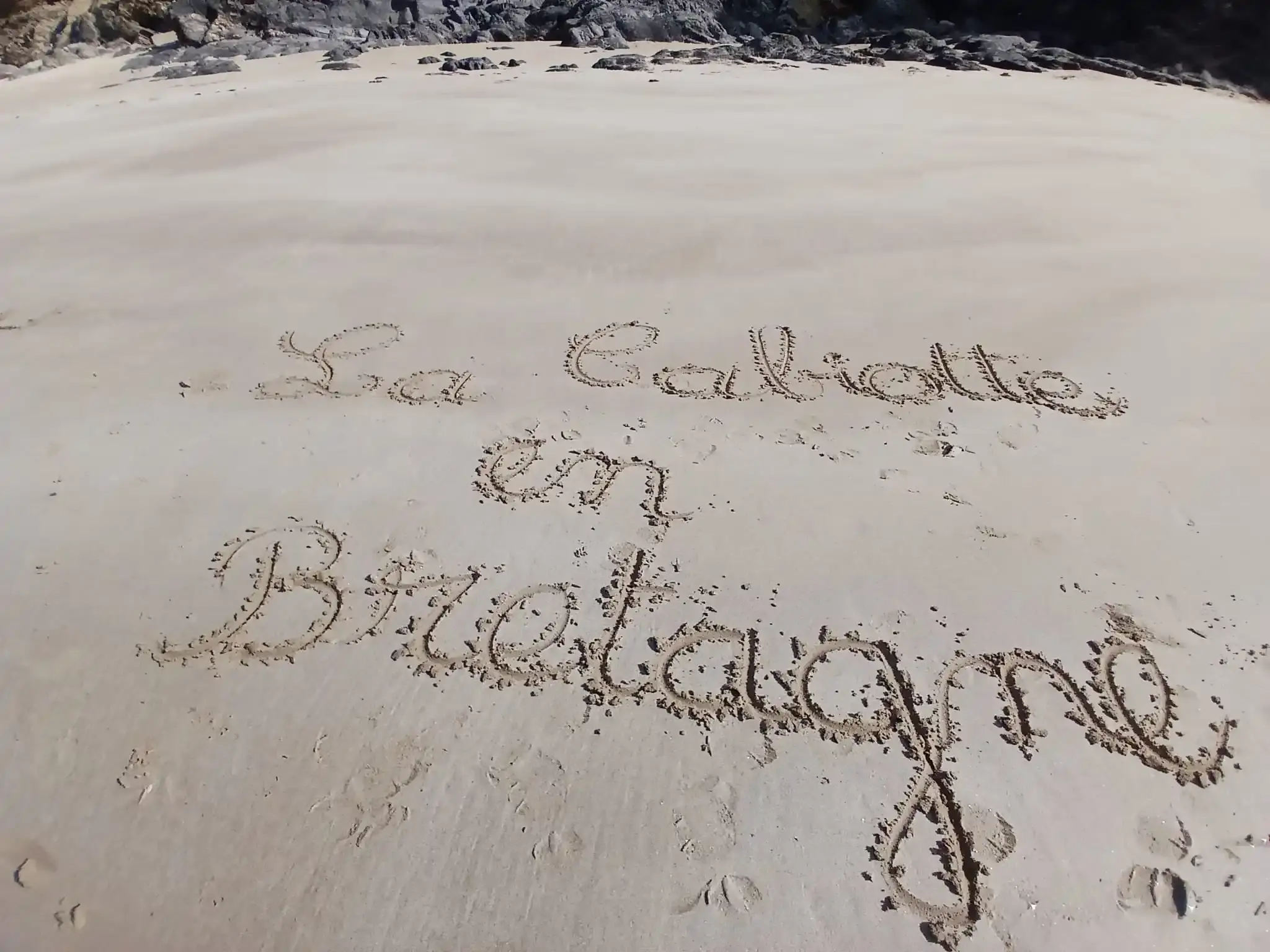 L’inscription « La Cabiotte en Bretagne » tracée dans le sable d’une plage
